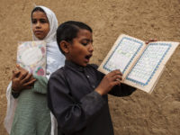 A girl standing in for her teacher supervises a lesson while a boy recites from a book at a school in a slum on the outskirts of Islamabad October 11, 2013. REUTERS/Zohra Bensemra (PAKISTAN - Tags: EDUCATION SOCIETY POVERTY) - RTX14721